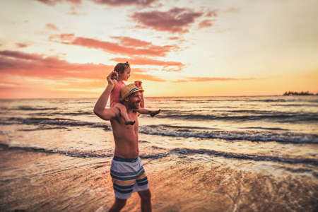 happy family at the beach a father and baby daughter having fun at sunsetの写真素材