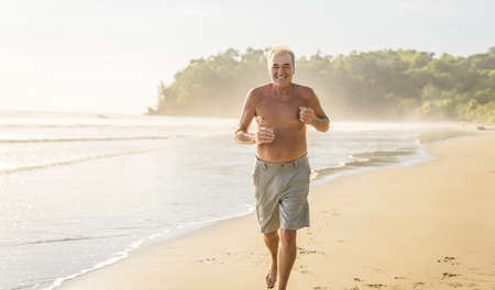 Senior men having great time on beach at the sunset doing joggingの写真素材