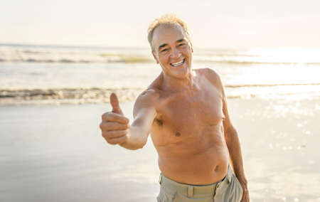 Senior men having great time on beach at the sunsetの写真素材