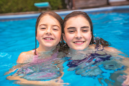 two sister having fun in Pool on the summer timeの写真素材