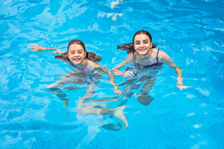 two sister having fun in Pool on the summer timeの写真素材