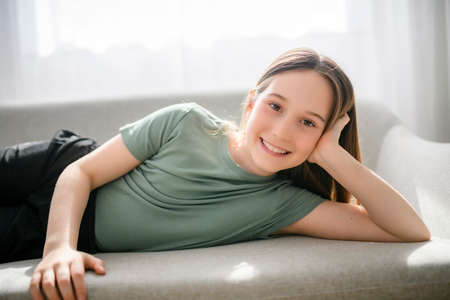 Beautiful pre teen girl relaxing on the sofa at homeの写真素材