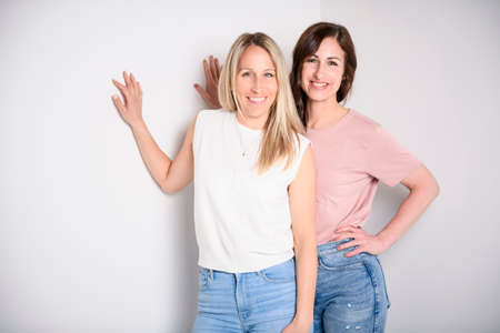 Two smiling best girl friends blond and brunette on white background. Closeup face portrait of two young beautiful women.の写真素材