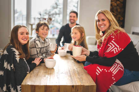 Family Enjoying Hot Drink In Cafe at home close to fireplace