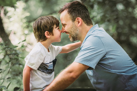 father with his little boy playing with him in nature.