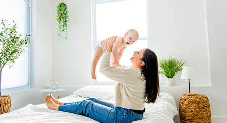 young beautiful mother with a baby boy on the bed at home