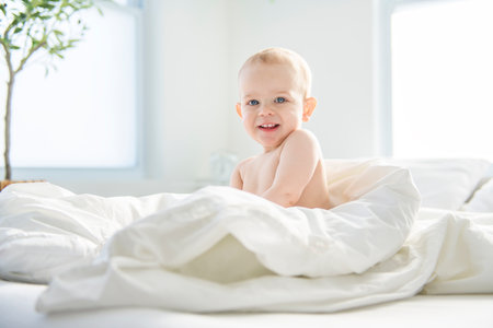 Adorable baby boy in white sunny bedroom.