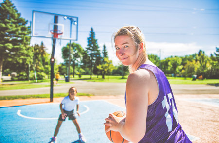 Mother and little daughter play basketball outside