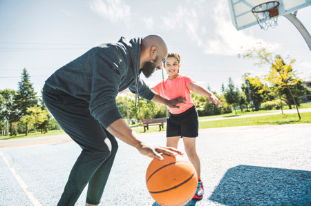 father and daughter playing basketball in the park