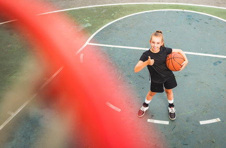 portrait of a kid girl playing with a basketball in parkの写真素材