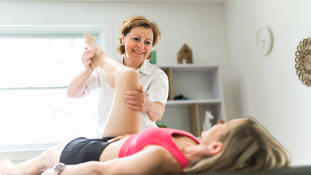 elderly Physiotherapist working with sporty patient in clinic