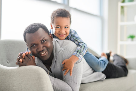 American father with little boy at home lay on sofaの写真素材