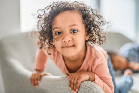 Little black girl concentrate watching tv alone in her living room.の写真素材