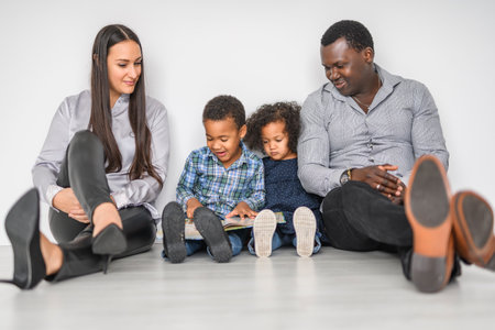 family with boy and girl child posing on photo shooting, sitting on the floor and reading bookの写真素材