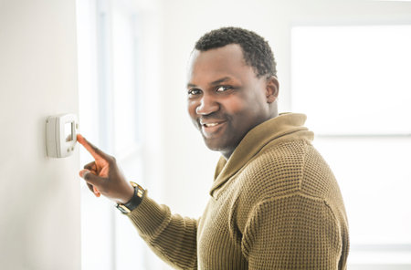 man choosing temperature on thermostat. Young focused guy pushing button home system.