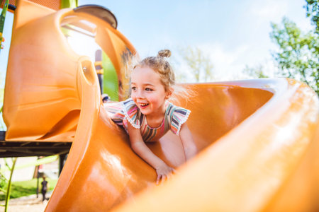 Happy kid slide on playground on summer season