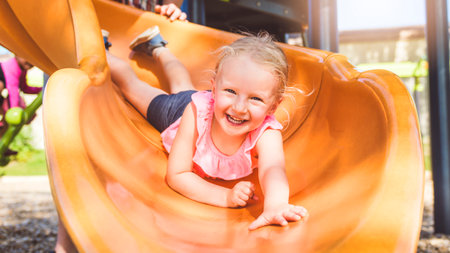 Happy kid slide on playground on summer season