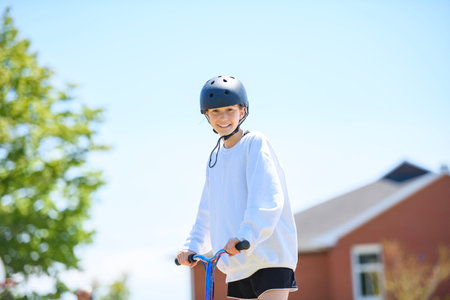 girl with helmet riding his scooter on a sunny dayの写真素材