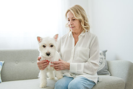 Cheerful retired senior woman with dog and enjoying time with pet at homeの写真素材