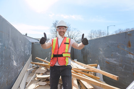 Construction Worker outside of house put old renovation material on big conteiner