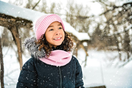 American child girl during snowfall in winter park