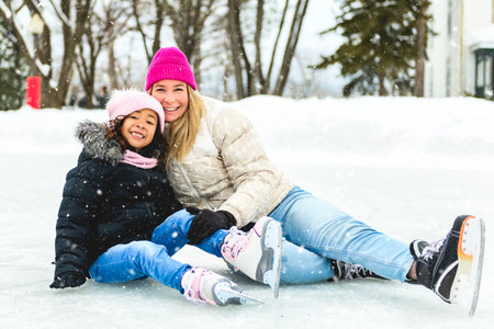 little girl skater in a winter park having fun with her daughterの写真素材