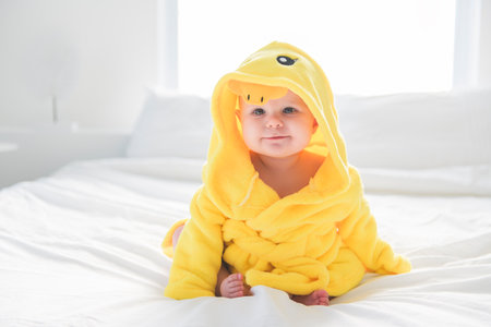 Adorable baby boy in white sunny bedroom wearing duck Bathrobeの写真素材