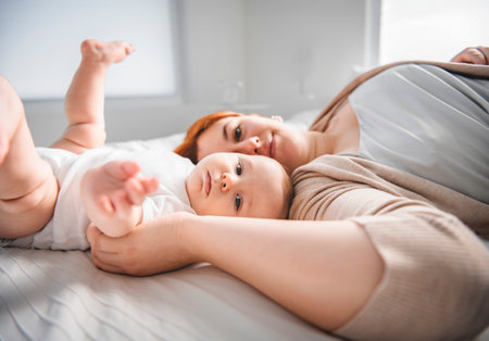 young beautiful mother with a baby boy on the bed at home