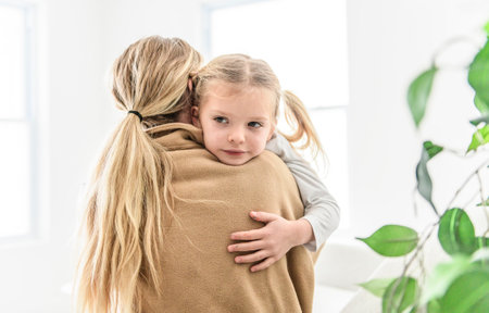 mother hugging and consoling little preschool frustrated girlの写真素材