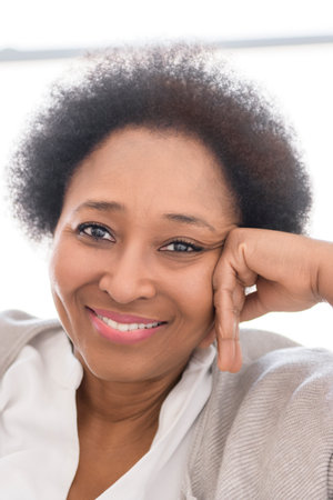 Black woman sitting on sofa at homeの写真素材
