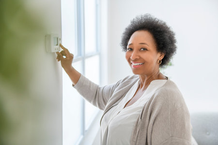 senior black American woman at home thermostat settingの写真素材