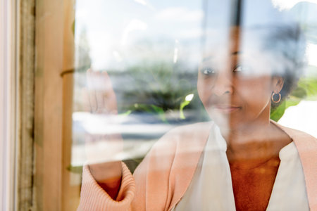 beautiful senior black American woman at home looking through window look sadの写真素材