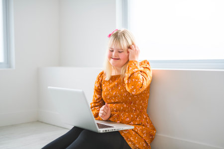 Girl with Down Syndrome doing homework at home, getting ready to go back to school with laptop