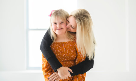 Mother and sweet down syndrome daughter girl at home
