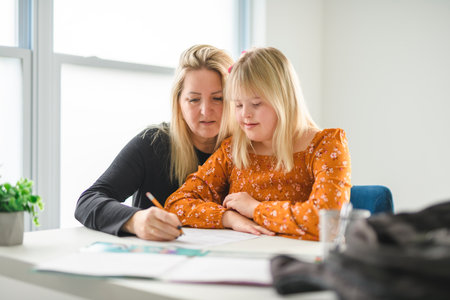 mother and girl with down syndrome drawing and smiling happily while enjoying development classの写真素材