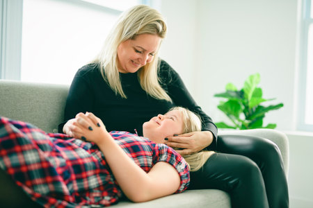 Mother and sweet down syndrome daughter girl at home sofaの写真素材