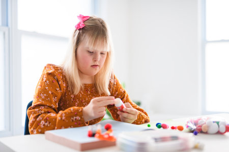 Portrait of beautiful little girl having down syndrome doing Arts and Craftsの写真素材