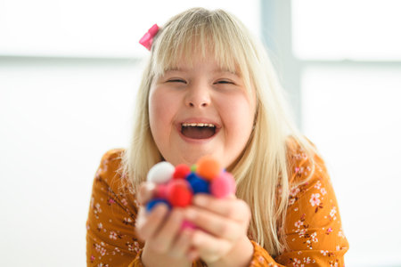 Portrait of beautiful little girl having down syndrome doing Arts and Craftsの写真素材
