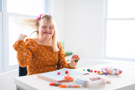 Portrait of beautiful little girl having down syndrome doing Arts and Craftsの写真素材