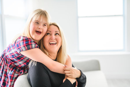 Mother and sweet down syndrome daughter girl at home sofaの写真素材