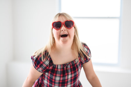 Portrait of beautiful little girl having down syndrome wearing heart glassesの写真素材