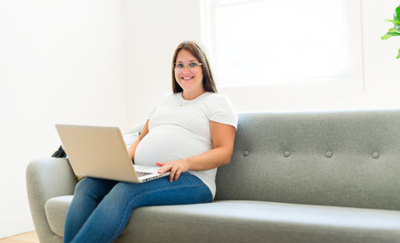 pregnancy, rest, people and expectation concept pregnant woman lying on sofa at home with laptop