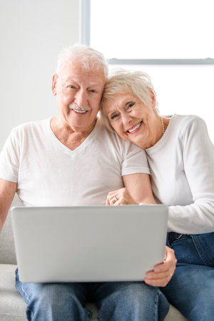 elder couple using online app, banking service on laptop, making payment, order, booking apartmentの写真素材