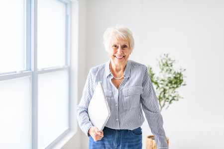 A senior women at the office holding laptopの写真素材