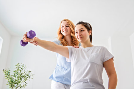 Modern rehabilitation physiotherapy at work with client holding dumbell