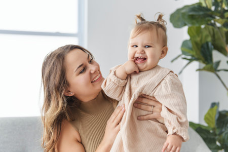 young beautiful mother with a baby girl having great time at homeの写真素材