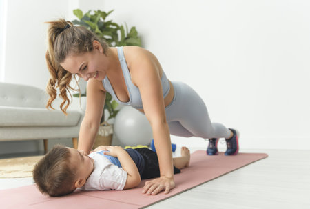 Sport Activities With Baby. Young Mom Exercising With Her Infant Son At Homeの写真素材