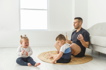 Tired young men with her childs play at homeの写真素材