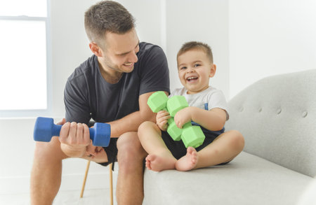 Little boy child having workout together with his father, exercising with dumbbells at homeの写真素材