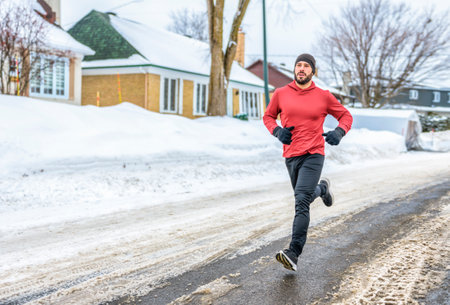 male runner jogging in cold winter forest wearing warm sporty running clothingの写真素材